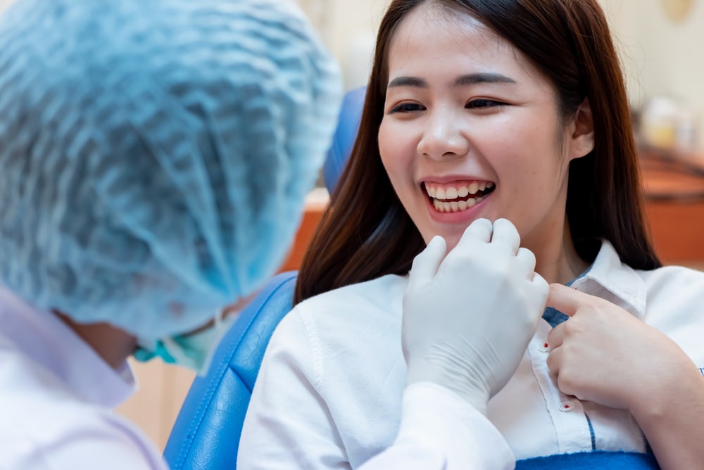 A dentist examining a woman's teeth after getting dental crowns in Rapid City